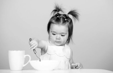 Photo for Cute baby food, babies eating. Portrait of cute Caucasian child kid with spoon. Hungry messy baby with plate after eating puree - Royalty Free Image