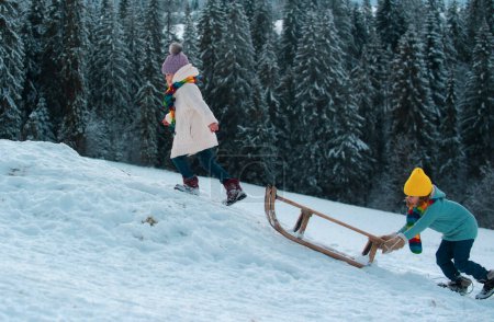 Téléchargez les photos : Des enfants en traîneau. Enfant garçon et fille joue dehors dans la neige. Paysage de Noël - en image libre de droit