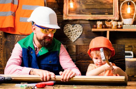 Photo for Father and son hammers nails with a hammer in a wooden board. Happy fatherhood - Royalty Free Image