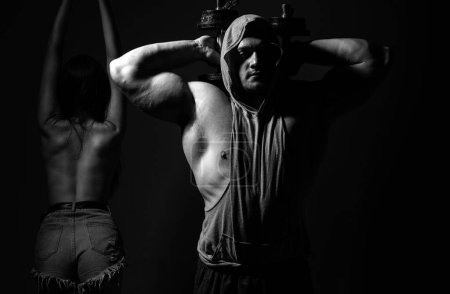 Foto de Los deportistas están haciendo ejercicio con pesas. Ajuste pareja haciendo ejercicio con mancuernas en estudio oscuro - Imagen libre de derechos