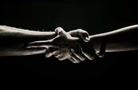 Photo for Hands gesturing on black background. Giving a helping hand. Support and help, salvation. Strength strong hads of two people at the time of rescue. Helping hand outstretched for salvation. Strong hold - Royalty Free Image