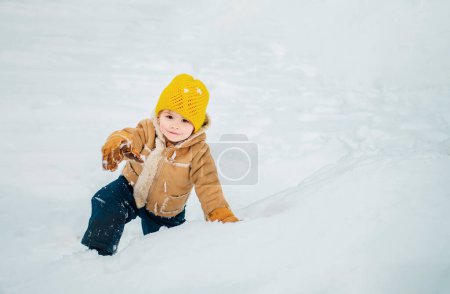 Foto de Niño feliz divirtiéndose en el campo de invierno con nieve. Emoción navideña. Feliz niño riendo jugando en un parque de invierno nevado en el día de Navidad
. - Imagen libre de derechos