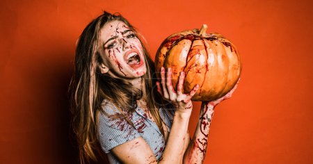 Téléchargez les photos : Femme au maquillage sanglant. Halloween fille sexy dans le sang avec citrouille. Horreur photo de filles sexy meurtriers tenir citrouille dans sa main - en image libre de droit