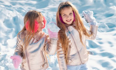 Foto de Niños en la nieve. Tema Navidad invierno año nuevo. Retrato de dos niñas jugando con nieve en invierno - Imagen libre de derechos