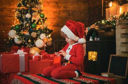 Photo for Little Santa Claus helper elf with a magic gift for Christmas. Christmas. Santa little helper. Happy family concept. Little genius. Little boy in Santa hat and costume having fun. New Year - Royalty Free Image