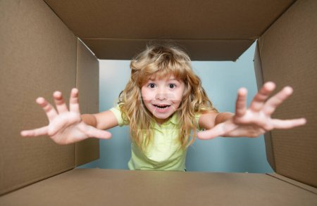 Photo for Happy child with cardboard box, unpacking parcel from internet store. Kids client satisfied with fast delivery service. Children expression surprised face - Royalty Free Image