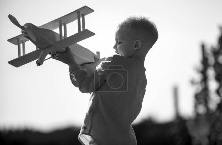 Foto de Niño piloto con juguete avión sueña con viajar en verano en la naturaleza. Los niños sueñan. El niño juega con un avión de juguete y sueña con convertirse en piloto. Concepto de imaginación de sueño infantil - Imagen libre de derechos
