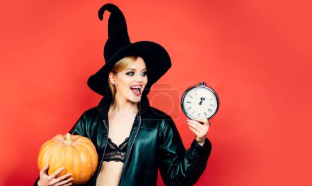 Téléchargez les photos : Joyeux gothique jeune femme en costume d'Halloween sorcière. Sorcière posant avec citrouille. Concept Halloween - en image libre de droit