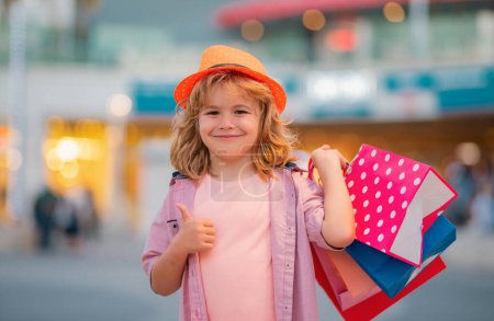 Foto de Comprando niños en la tienda de moda. Niño de moda con bolsa de compras al aire libre. Pequeño niño comprador - Imagen libre de derechos