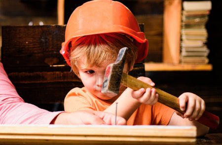 Foto de Pequeño reparador divertido con martillo. Trabajador de construcción de niños. Niño use un martillo para clavar - Imagen libre de derechos
