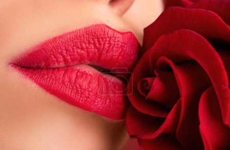 Téléchargez les photos : Lèvres avec rouge à lèvres gros plan. Belle femme lèvres avec rose. Parfait peau propre, maquillage des lèvres sexy. Magnifique portrait spa avec tendre fleur de rose rouge - en image libre de droit