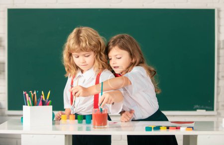 Photo for School children drawing a colorful pictures with pencil crayons in classroom. Portrait of cute pupils enjoying art and craft lesson. Little artists painting, kids drawing art - Royalty Free Image