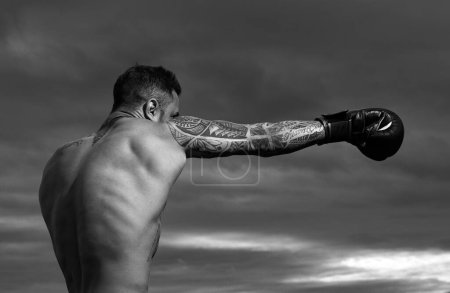 Foto de Boxeador atleta golpeando. Retrato de boxeador masculino. Hombre musculoso en guantes de boxeo al aire libre. Boxeador atlético. Golpe de boxeo - Imagen libre de derechos