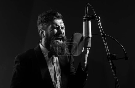 Photo for Singer man singing with a microphone in recording studio - Royalty Free Image