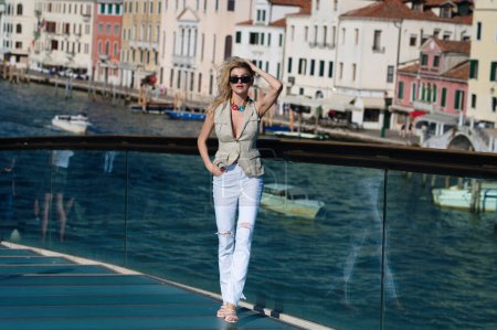 Foto de Encantadora joven caminando en Venecia, Italia. Vacaciones de verano italianas. Mujer de moda en la calle Venice. Mujer viajera en sus vacaciones de verano en Venecia - Imagen libre de derechos