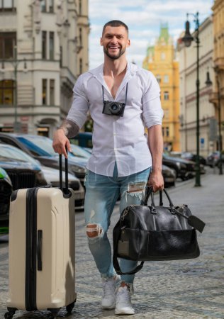 Foto de Concepto de viaje. Turista con bolsa de viaje viajando. Hombre con maleta caminar en la calle de la ciudad al aire libre. Viajar al extranjero los fines de semana - Imagen libre de derechos