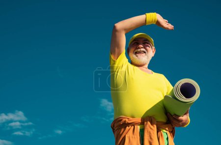 Téléchargez les photos : Homme âgé pratiquant le sport sur fond de ciel bleu. Sportif. Sain et sportif. Grand-père pensionné. Comme le sport - en image libre de droit