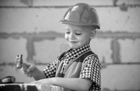 Foto de Retrato de pequeño constructor en sombreros con instrumentos para la renovación en la construcción. Constructor, carpintero con herramientas de construcción. Reparación casa - Imagen libre de derechos