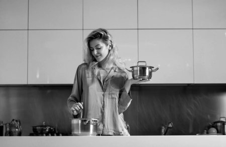 Téléchargez les photos : Femme cuisinant dans une cuisine. Femme au foyer sexy le matin. Travaux ménagers - en image libre de droit