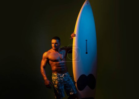 Téléchargez les photos : Surfboard homme sexy. Un type avec une planche de serf. Concept vacances d'été. Surfeur avec une planche de surf. Portrait d'athlète séduisant avec planche de serf. Plage masculine loisirs, vacances d'été - en image libre de droit