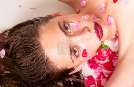 Téléchargez les photos : Femme sensuelle sur fond de roses printanières. Séduisante et sexy fille de la nature regardant la caméra. Une peau parfaite - en image libre de droit