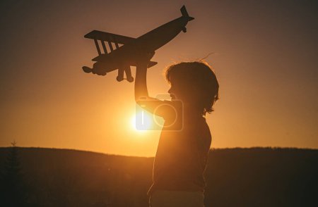 Téléchargez les photos : Enfant pilote aviateur avec avion rêve de voyager au coucher du soleil - en image libre de droit