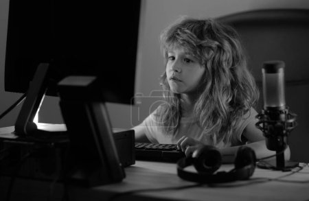 Foto de Niño en la pantalla de la computadora PC. Lindo niño preescolar está viendo la película por escritorio antes de dormir. Retrato de un niño lindo mientras escribe en el teclado - Imagen libre de derechos