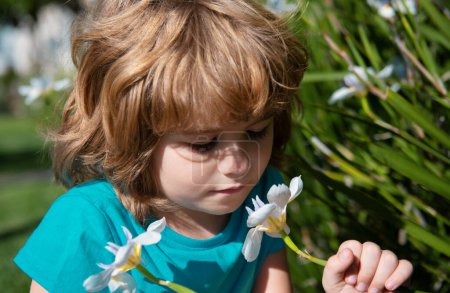 Téléchargez les photos : Enfant avec narcisse blanche. Fleurs printanières. Allergie aux fleurs. Petit garçon sentant les fleurs en plein air - en image libre de droit