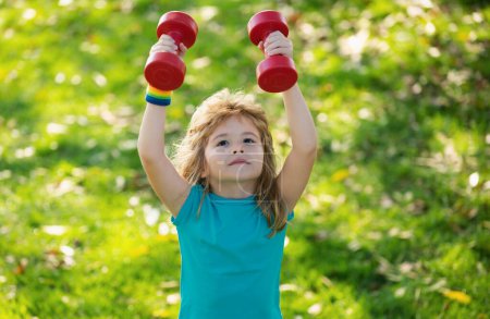 Photo for Healthy kid boy with dumbbell exercise outdoor. Little child practice dumbbells exercises in park - Royalty Free Image