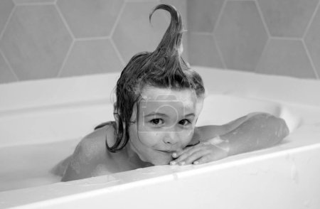 Foto de Baño de niños. Niño bañándose en un baño con espuma. Funny cara de niño bañado en el baño - Imagen libre de derechos