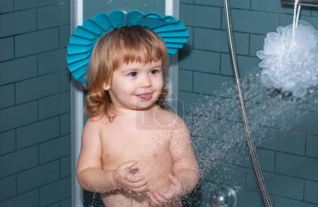 Foto de Niño pequeño bañándose en jabones. Divertido bebé niño bañado en espuma y lavado en la bañera en casa - Imagen libre de derechos