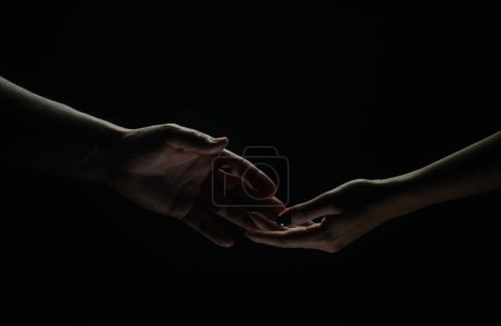 Foto de Two hands reaching toward. Helping hand outstretched for salvation on isolated black background. Close up of man and woman hand touch with fingers. Man and woman holding hands - Imagen libre de derechos