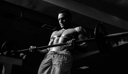 Photo for Fit man doing biceps lifting barbell. Muscular man working out in gym doing exercises, strong male naked torso abs - Royalty Free Image