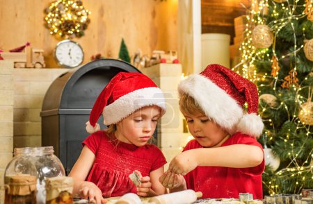 Photo for Cute kids in santa hats preparation holiday dinner for family. Santa cook. Cookie on Christmas Eve as a thank Santa gift for leaving presents to a grateful boy or girl - Royalty Free Image