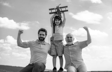 Foto de Tres generaciones de hombres juntos, retrato de un hijo sonriente, padre y abuelo con un avión de juguete. Niño jugando con avión. Aventura familiar, imaginación, innovación e inspiración - Imagen libre de derechos