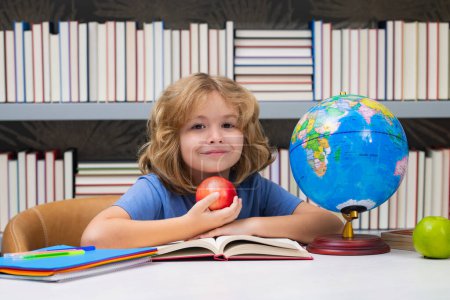 Photo for School boy with books and apple in library. School child student learning in class, study english language at school. Elementary school child. Portrait of funny pupil learning - Royalty Free Image