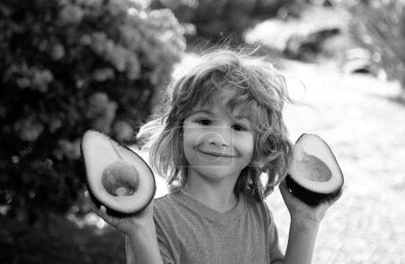 Foto de Niño feliz en el patio divirtiéndose con aguacate. Niños verano vitamina - Imagen libre de derechos