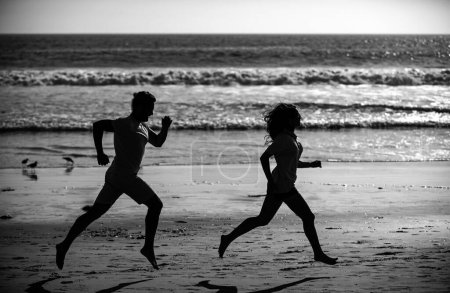 Téléchargez les photos : Couple courant sur la plage. Sport et mode de vie sain, amis silhouette jogging au coucher du soleil sur la plage - en image libre de droit