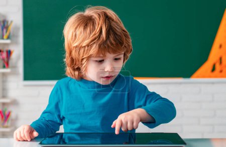 Foto de Niño escolar con tableta en el aula de la escuela. Niños aprendiendo. Niños de primaria - Imagen libre de derechos