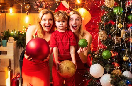 Foto de Mujer emocionada y niño encantador con decoración de Navidad están de pie junto al árbol de navidad. Decoración de Navidad - Imagen libre de derechos
