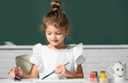 Foto de Little girls drawing a colorful pictures with pencil crayons in school classroom. Painting kids. Childhood learning, kids artistics skills - Imagen libre de derechos