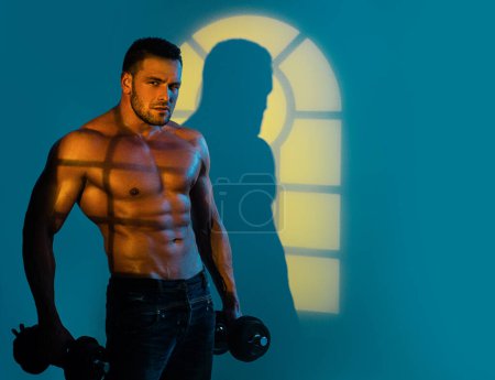 Photo for Muscular sexy man with naked torso is posing with dumbbell. Muscular and sexy torso of young man having perfect athletic body. Fitness concept. Male hunk - Royalty Free Image
