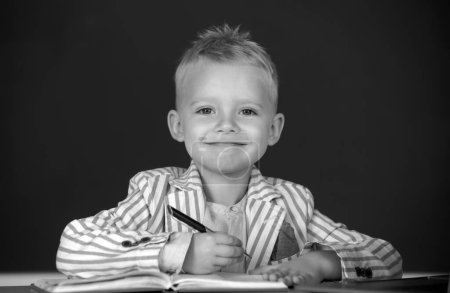 Photo for Kid writing in class. Child at school. Kid is learning in class on background of blackboard - Royalty Free Image