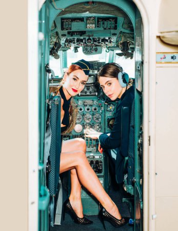 Photo for Pilot and Stewardess. Wishes a successful flight. Avia company persons crew pilots stewardess airplane command civil aviation. Beautiful Smiling Woman Pilot With Headset Sitting in Cabin - Royalty Free Image