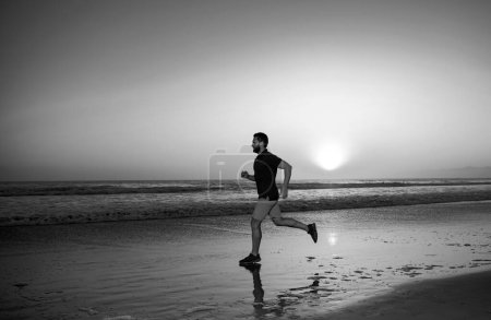 Photo for Active healthy runner jogging outdoor. Young and active jogger running. Fit male fitness runner during outdoor workout with sea sunset background - Royalty Free Image