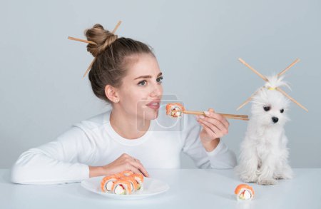Téléchargez les photos : Japanese woman sushi style. Eating japanese sushi set. Beauty young woman and dog eating sushi with a chopsticks, isolated on white. Sushi roll with chopsticks. Healthy Japanese food - en image libre de droit