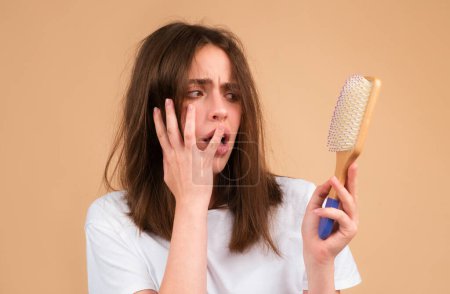 Téléchargez les photos : Problème de perte de cheveux traitement. Portrait de femme avec un peigne et des cheveux problématiques - en image libre de droit