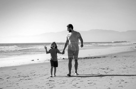 Foto de Padre e hijo caminando sobre el mar. Papá y el niño tomados de la mano y caminando juntos - Imagen libre de derechos