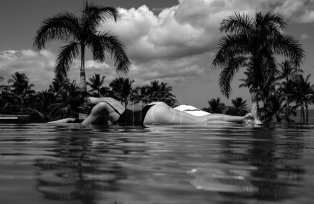 Téléchargez les photos : Femme sexy profitant de vacances à la plage de luxe dans un hôtel resort avec piscine et cap tropical près de la plage de la mer - en image libre de droit
