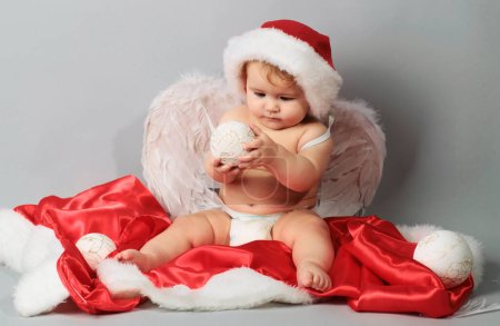 Téléchargez les photos : Noël de bébé. Bébé drôle mignon dans un chapeau de Père Noël. Nouvel An enfant joyeux - en image libre de droit